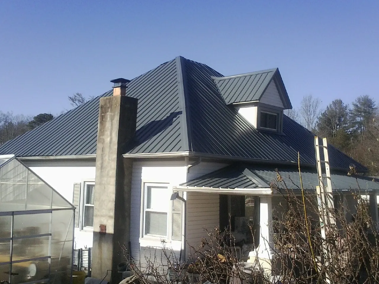 Dark blue standing seam metal roof on a white farmhouse with dormer — Slate & Tile Roof Repair by Roofing Brothers in Robins
