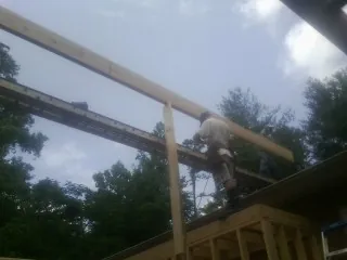 Carpenter setting a ridge beam over a new addition frame — Ice Dam Removal by Roofing Brothers in Robins