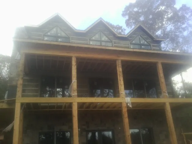 Dormers and porch framing on a large log home under construction — Roof Coating work by our crew in Robins