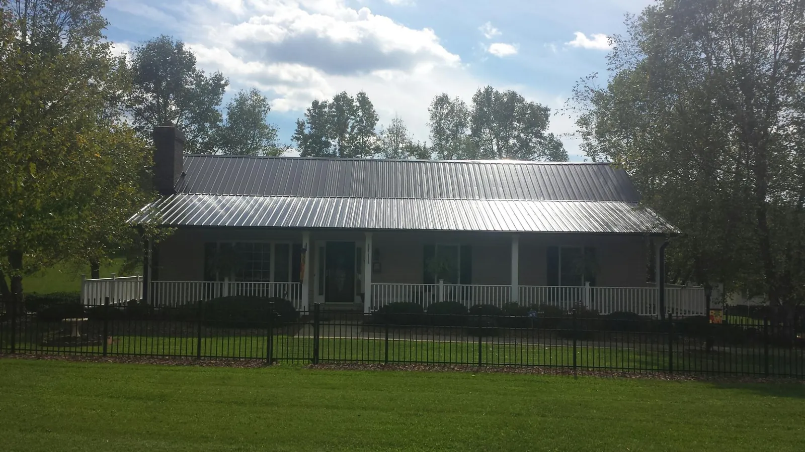Gray metal roof on a brick ranch with a full width front porch — Gutter Guard Installation work by our crew in Robins
