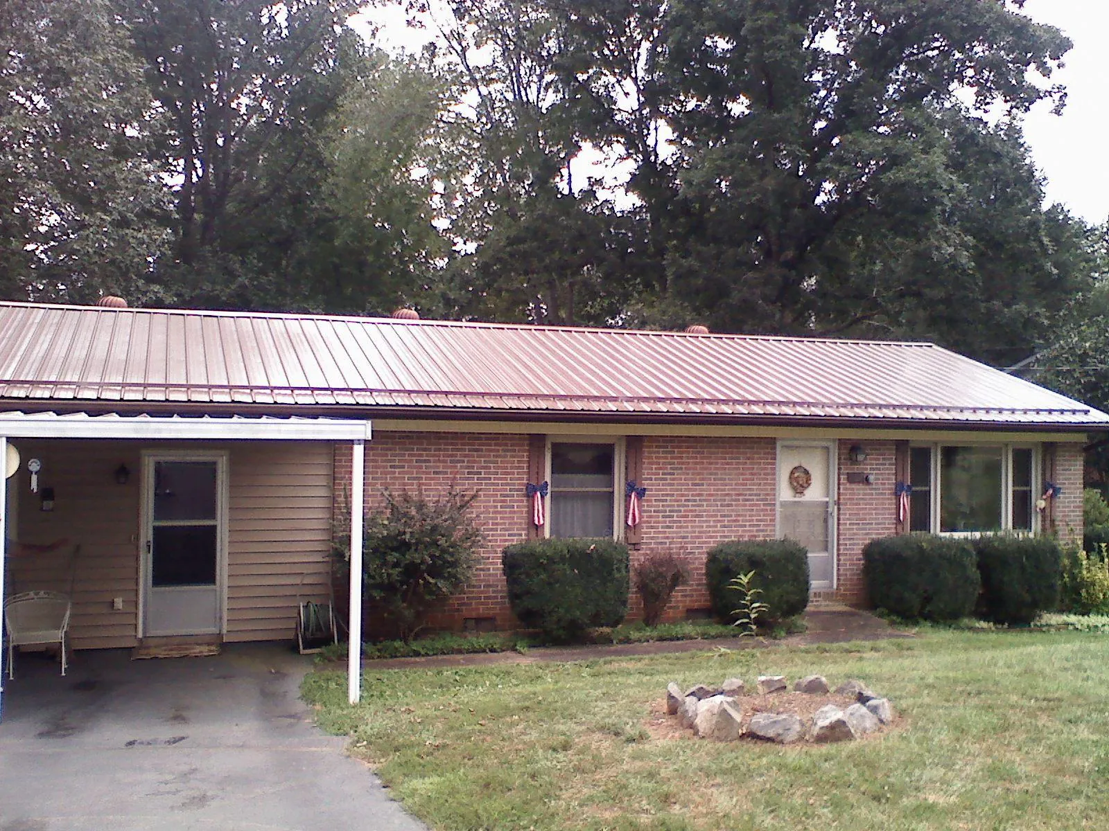 Bronze metal roof and carport on a brick ranch home — Roof Repair work by our crew in Robins