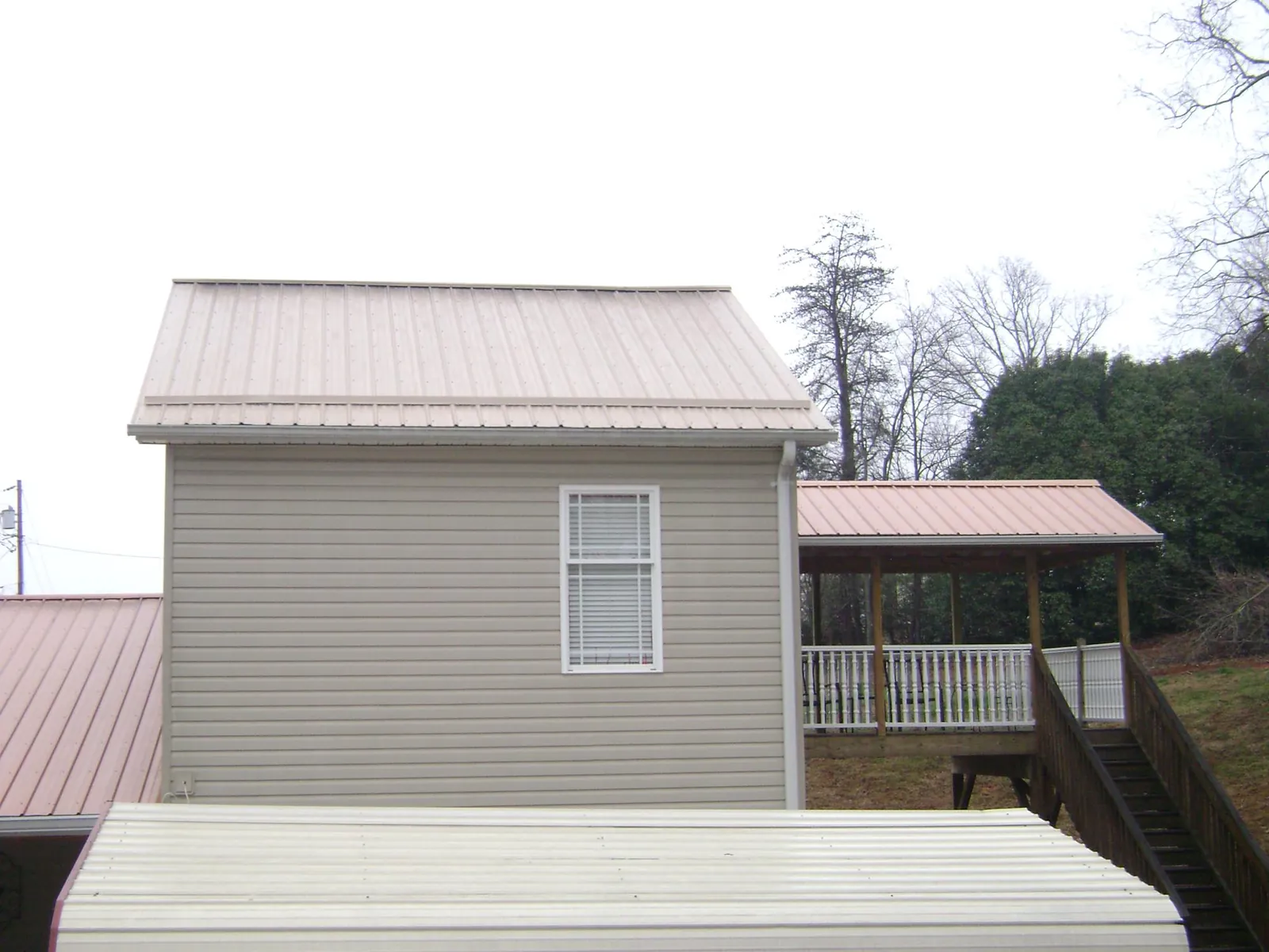 Tan metal roofs on a two story addition and attached porch, from a Roof Replacement job in Robins